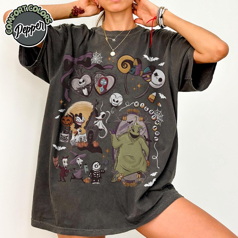 May include: Dark gray t-shirt featuring a colorful graphic design with characters from "The Nightmare Before Christmas." The design includes Jack Skellington, Sally, Oogie Boogie, and other Halloween-themed elements. The shirt has the text "NIGHTMARE" in a circular pattern.
