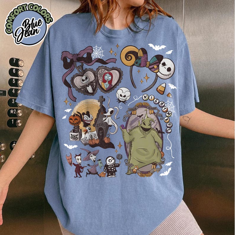 May include: Blue graphic t-shirt featuring characters from The Nightmare Before Christmas. The design includes Jack Skellington, Sally, Oogie Boogie, and Zero. The shirt has the words "NIGHTMARE" and "Blue Jean" printed on it.