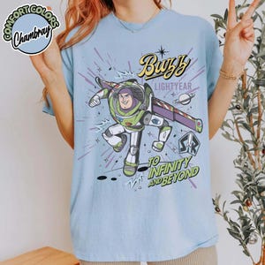 May include: Light blue t-shirt featuring Buzz Lightyear from Toy Story. The graphic includes the text "Buzz Lightyear" and "To Infinity and Beyond" with a cartoon image of Buzz in his spacesuit.