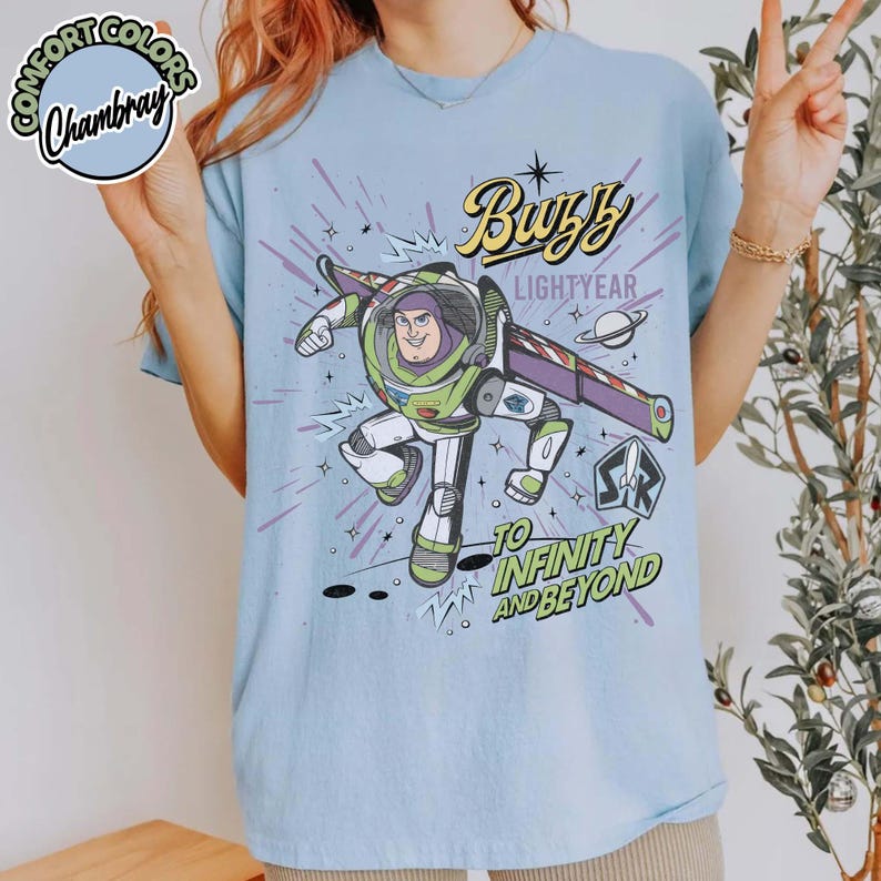 May include: Light blue t-shirt featuring Buzz Lightyear from Toy Story. The graphic includes the text "Buzz Lightyear" and "To Infinity and Beyond" with a cartoon image of Buzz in his spacesuit.