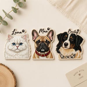 May include: Three custom pet portrait ornaments featuring a white cat named Luna, a fawn French Bulldog named Max with a red collar, and a tricolour Australian Shepherd named Bailey, each with a small paw print icon next to their name.
