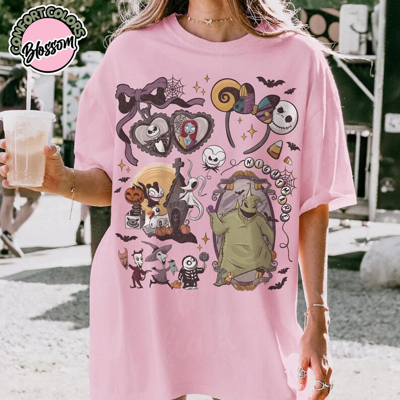 May include: Pink t-shirt featuring a colorful graphic design with characters and elements from "The Nightmare Before Christmas." The design includes Jack Skellington, Sally, Oogie Boogie, and other iconic imagery. The shirt has a relaxed fit.