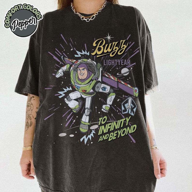 May include: Dark gray t-shirt featuring Buzz Lightyear from Toy Story. The graphic shows Buzz in his spacesuit with the words "Buzz Lightyear" and "To Infinity and Beyond" in yellow and white. The shirt has a vintage, distressed look.