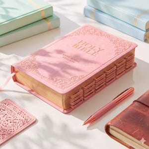 tabbed pink King James Version Holy Bible with gold lettering and decorative border. The Bible has labeled tabs and a pink ribbon bookmark.