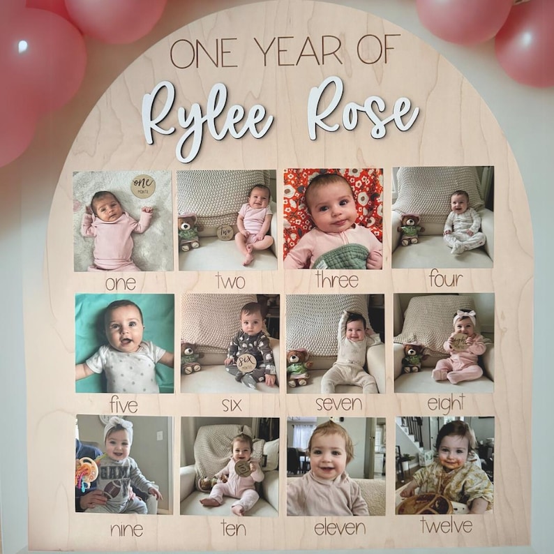K&ouml;nnte beinhalten: Eine h&ouml;lzerne Foto-Anzeigetafel mit dem Text "ONE YEAR OF Rylee Rose" und zw&ouml;lf Fotoschlitzen. Jeder Schlitz enth&auml;lt ein Foto eines Babys mit der Monatsnummer darunter. Rosa Ballons sind im Hintergrund.