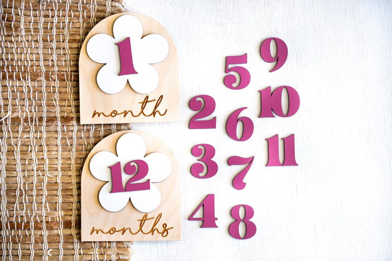 Two wooden monthly milestone markers for baby's first year photos with 12 interchangeable tropical pink numbers.