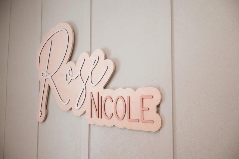 Outline custom nursery name sign with the name Rose Nicole in white and pink on natural wood backer