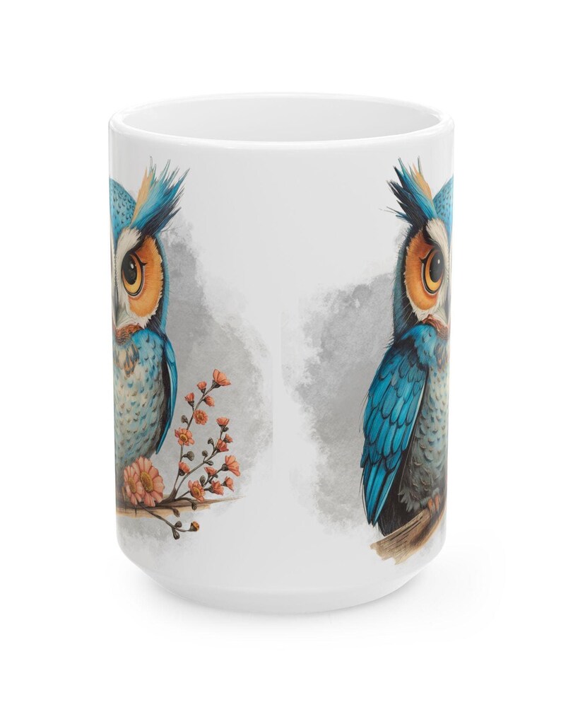 May include: White ceramic mug featuring a detailed illustration of a blue and orange owl perched on a branch with orange flowers. The owl has large yellow eyes and is set against a soft gray background.