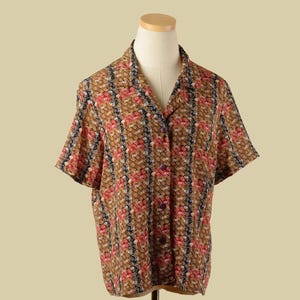 May include: A short-sleeved button-up shirt with a brown, red, and blue geometric pattern.