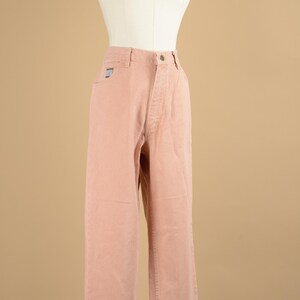 May include: A pair of light pink straight leg jeans. The jeans have a high waist and a button fly.