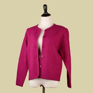 May include: A magenta cardigan with a button-up front and a floral embroidered design.
