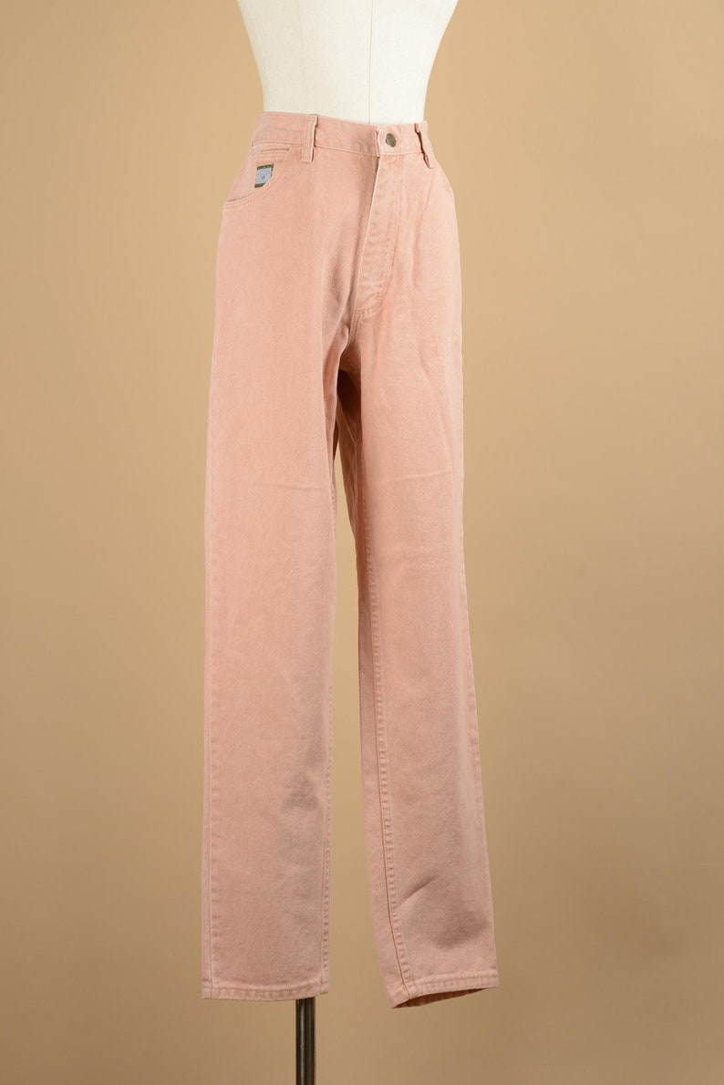 May include: A pair of light pink straight leg jeans. The jeans have a high waist and a button fly.