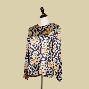 May include: A long-sleeved blouse with a floral print on a navy blue background. The flowers are in shades of pink, orange, and green.
