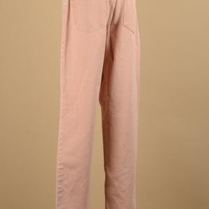 May include: A pair of light pink straight leg jeans. The jeans have a classic five-pocket design and a button fly.
