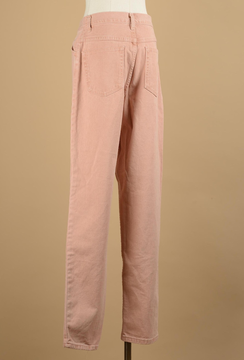 May include: A pair of light pink straight leg jeans. The jeans have a classic five-pocket design and a button fly.