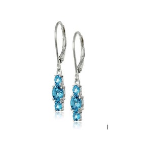 May include: A pair of silver-toned drop earrings. Each earring features three oval-shaped, light blue gemstones. The earrings have a lever-back closure and are displayed against a white background.