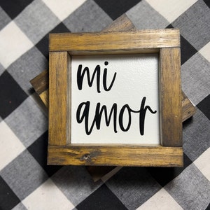 May include: A wooden framed sign with the words "mi amor" in black script on a white background.