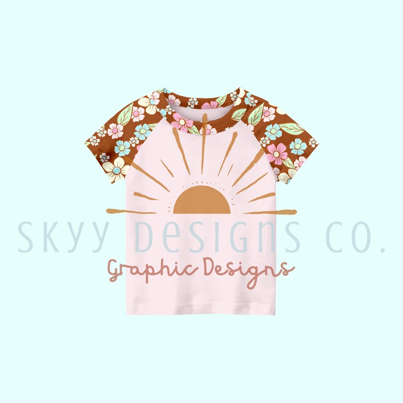 May include: A pink baby t-shirt with a brown floral print on the sleeves and a graphic of a sun with rays on the front. The text "sky designs co. Graphic Designs" is printed below the sun graphic.