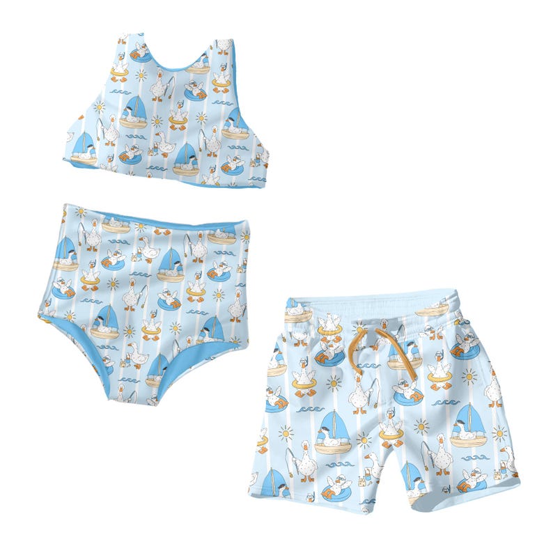 May include: A light blue swimwear set featuring a repeating pattern of cartoon geese on boats, in inner tubes, and fishing. The set includes a bikini top, high-waisted bottoms, and swim trunks with a drawstring.
