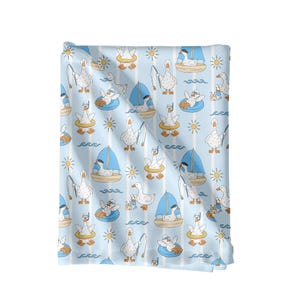 May include: A light blue fabric with a repeating pattern of cartoon geese enjoying various summer activities. The geese are fishing, sailing, and relaxing in the sun. The design includes sailboats, suns, and waves.