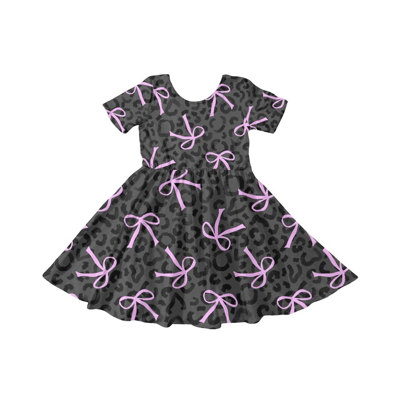 May include: A short-sleeved dress with a dark grey leopard print and light pink bows. The dress has a round neckline and a flared skirt, suitable for casual wear.