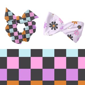 May include: Two hair scrunchies, one with a black and white checkered pattern and the other with a floral pattern. The checkered scrunchie is pink, orange, and blue. The floral scrunchie is light purple with pink and white flowers.