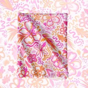 May include: A white fabric with a pink and orange floral pattern. The fabric is folded in half and the pattern is visible on both sides.