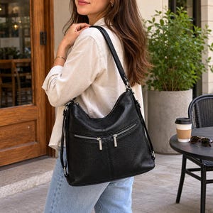 Pode incluir: Uma bolsa de ombro em couro preto granulado com dois bolsos frontais horizontais com fecho de correr e ferragens prateadas, um compartimento principal com fecho e alças ajustáveis que permitem várias opções de transporte.