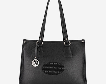 May include: A black leather tote bag with a silver charm and a textured oval patch on the front.
