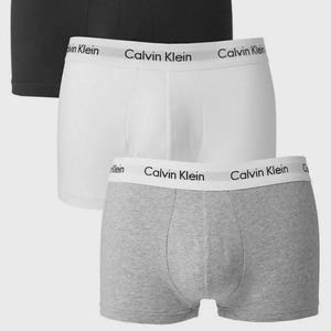 May include: Three pairs of Calvin Klein boxer shorts in black, white, and grey. Each pair has the Calvin Klein logo on the waistband. The underwear is made of a soft, comfortable material.