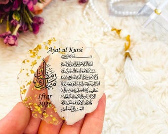 May include: A decorative, scalloped-edge resin piece with gold leaf accents. The piece features Arabic calligraphy and the words "Ayat ul Kursi" and "Iftar 2026". A white pearl prayer bead necklace and flowers are in the background.