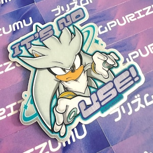 May include: A silver and blue sticker featuring a cartoon character with the text "It's No Use!" printed on it.