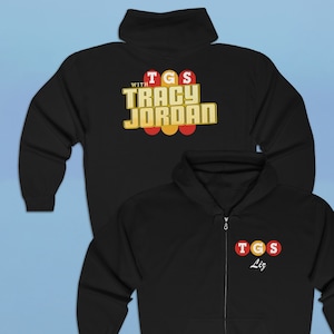 May include: Black zippered hoodie with a graphic print on the front and back. The front graphic says "TGS Liz" and the back graphic says "With TGS Tracy Jordan".