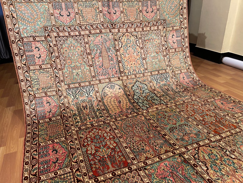 May include: An intricately designed rug with a repeating pattern of stylized trees and floral motifs in shades of pink, green, and brown. The rug has a detailed border and a traditional aesthetic.