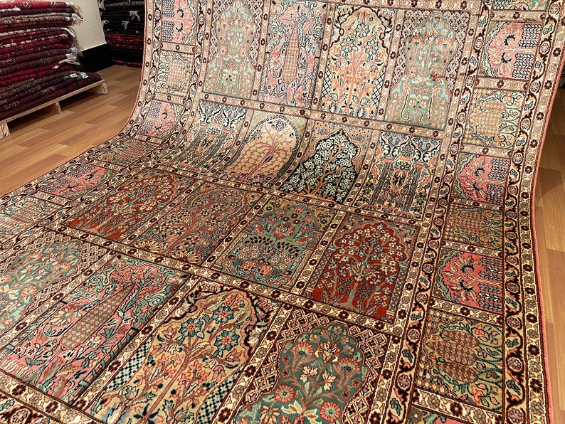 May include: An intricately designed rug with a repeating pattern of arched panels, each featuring floral and tree motifs in shades of red, pink, green, and beige. The rug has a detailed border and a warm color palette, suggesting a traditional or oriental style.