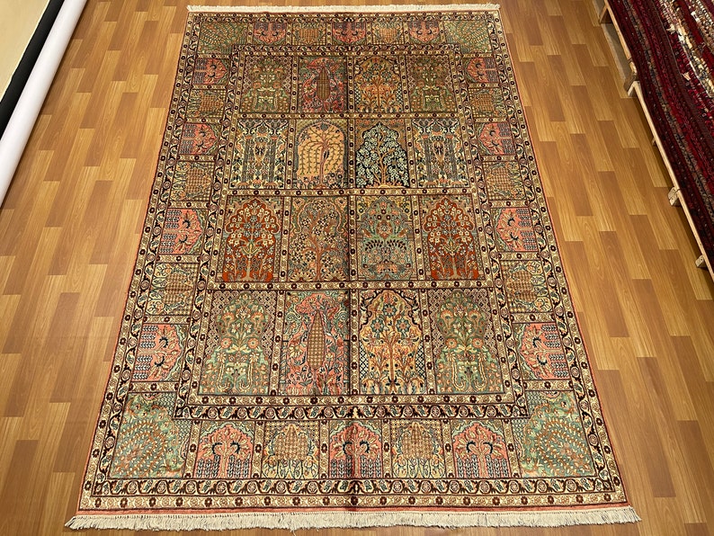 May include: An intricately designed area rug with a repeating pattern of trees and floral motifs in shades of red, green, and beige. The rug has a detailed border and a rectangular shape.