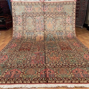 May include: An intricately designed area rug with a repeating pattern of stylized trees, floral motifs, and arched panels in shades of green, red, pink, and beige. The rug has a detailed border and a fringed edge.