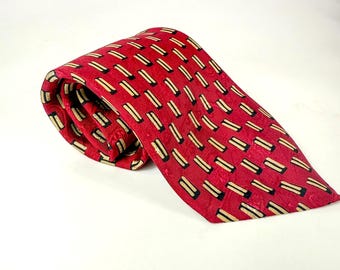 May include: Rolled red tie with a repeating pattern of black and tan rectangles. The tie is made of a smooth fabric and is displayed against a white background. The tie is a classic accessory.