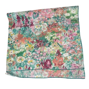 Puede incluir: Un pañuelo cuadrado con un estampado floral vibrante estilo acuarela, con flores en tonos rosa, coral, amarillo y blanco sobre un fondo verde azulado. La tela tiene un dobladillo acabado en color verde azulado en los bordes.
