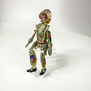 Figura articulada de arlequín bufón esmaltada en tono plateado, hecha en Italia.