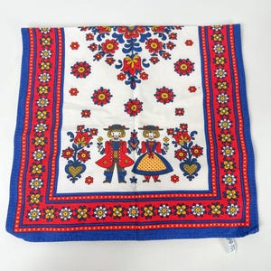 Può includere: Un tessuto decorativo quadrato bianco con un bordo blu. Il tessuto presenta un motivo floreale rosso e blu, con due figure in abiti tradizionali. Il bordo ha un motivo floreale ripetuto.