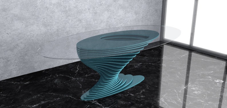 May include: A teal blue glass-top table with a unique, swirling, layered base. The table is oval shaped and sits on a black marble floor.