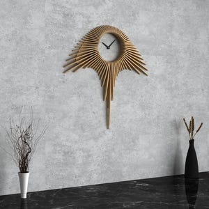 Peut inclure: Une horloge murale moderne avec un design unique en forme de soleil éclatant composé de lattes de bois. L'horloge a un cadran rond avec des aiguilles noires et un fond blanc. L'horloge est montée sur un mur gris avec un sol noir.