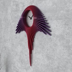 Könnte beinhalten: Eine moderne Wanduhr mit einem einzigartigen Design. Das Zifferblatt der Uhr ist ein Kreis mit einem roten und violetten Farbverlauf, und die Zeiger sind schwarz. Die Uhr ist an einer weißen Wand montiert.