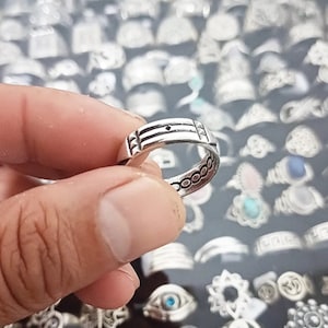 May include: A silver ring with a textured design. The ring is simple and elegant, with a smooth finish.