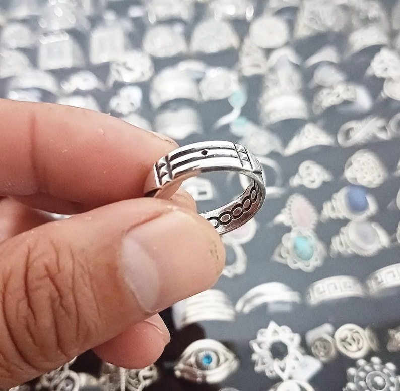 May include: A silver ring with a textured design. The ring is simple and elegant, with a smooth finish.