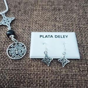 Puede incluir: Un collar de plata con un colgante de pentagrama y un par de pendientes a juego. Los pendientes y el colgante presentan un diseño en forma de estrella. El texto "PLATA DELEY" está en una tarjeta blanca.