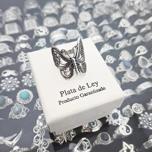 Puede incluir: Un anillo de plata en forma de mariposa en una caja blanca con el texto "Plata de Ley Producto Garantizado".
