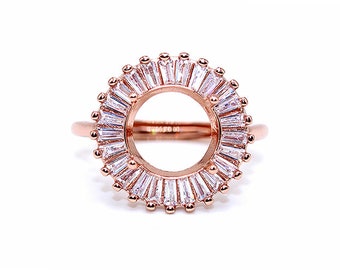 May include: Rose gold ring featuring a circular design with a central open space. The ring is adorned with numerous baguette-cut, clear gemstones arranged in a sunburst pattern. Small, round accents are placed around the outer edge of the ring.