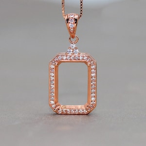 Puede incluir: Un colgante de oro rosa con un marco rectangular engastado con piedras de circonita cúbica transparentes. El colgante está diseñado para contener una piedra preciosa u otro inserto.
